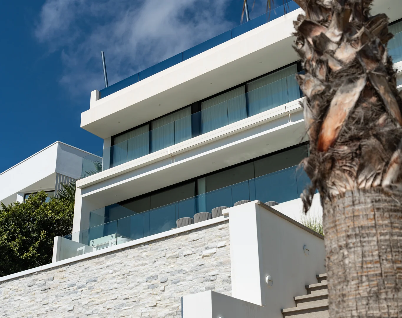 Modern white villa façade with glass and palm in Cas Mut, near Ibiza Town