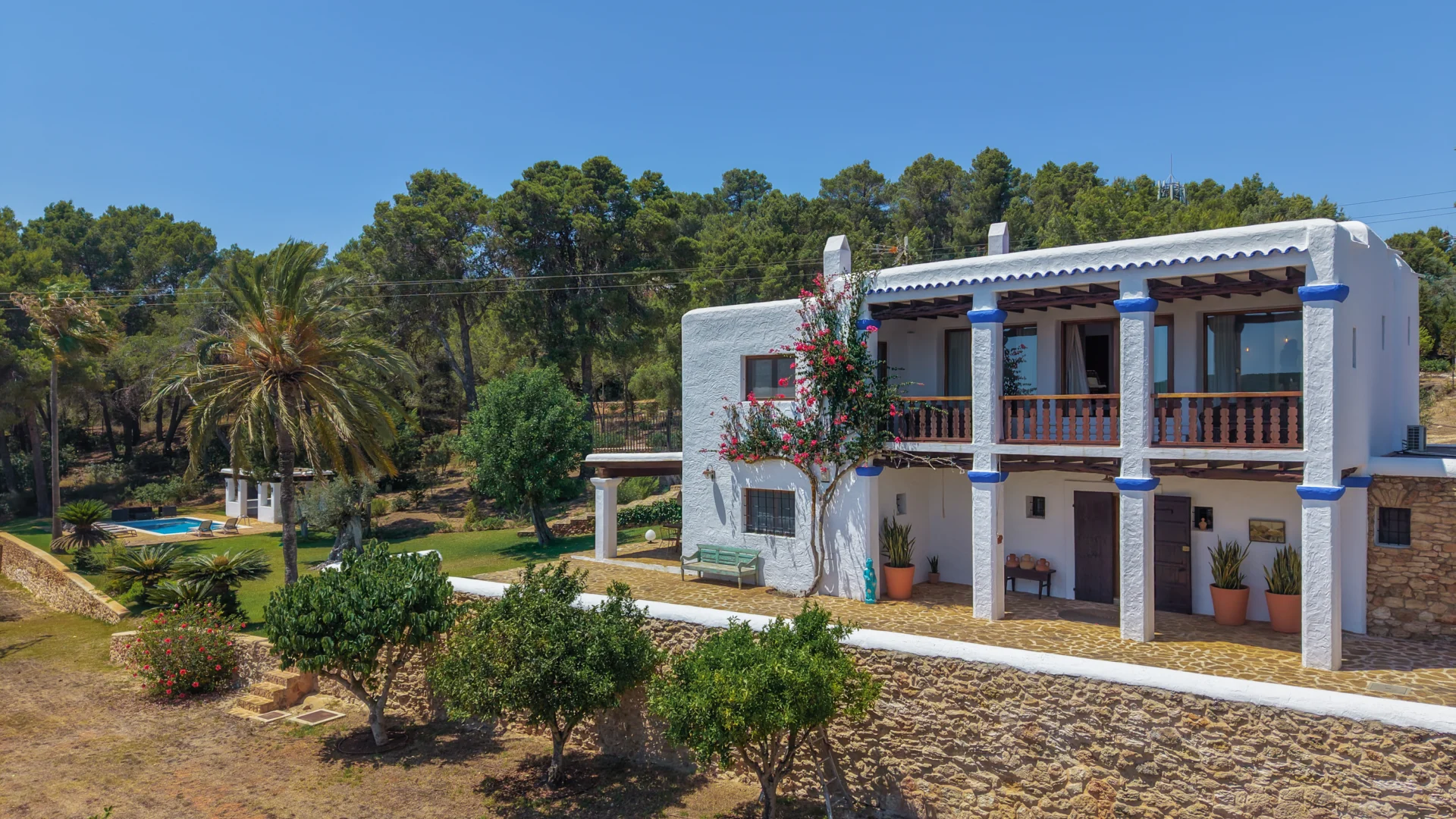 Two-storey finca façade with blue columns and bougainvillea near San Carlos, Ibiza