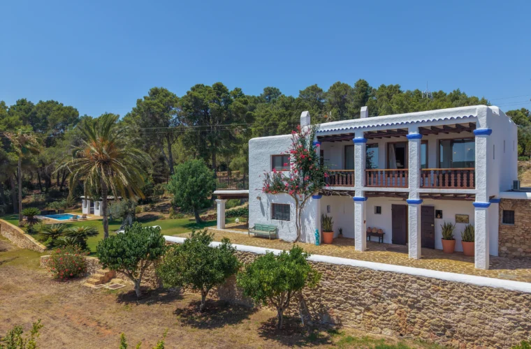 Two-storey finca façade with blue columns and bougainvillea near San Carlos, Ibiza